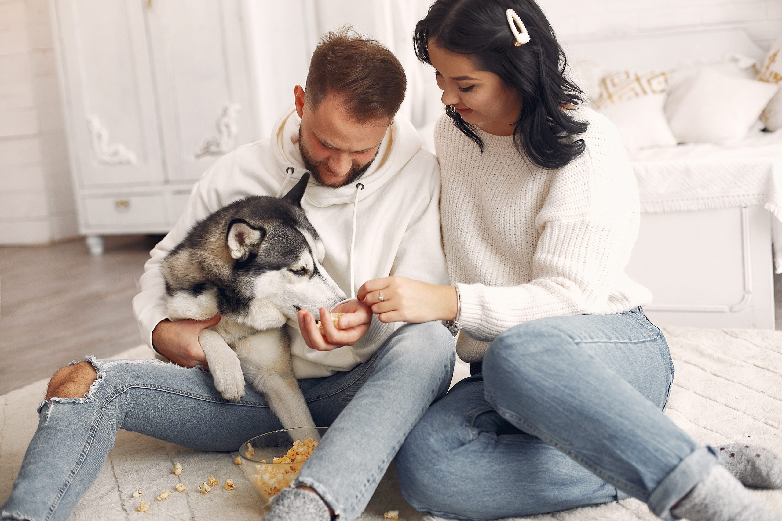 Cute couple in a bedroom. Lady in a white sweater. Pair with a dog